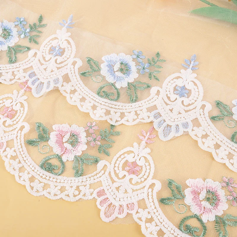 Ivory Scroll and Pastel Bloom Lace Border — Photographed decorative trim sample; verify colour and construction with a physical sample
