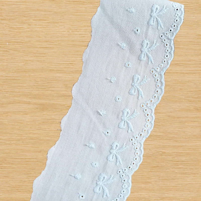 Pale Blue Bow Eyelet Trim — Photographed decorative trim sample; verify colour and construction with a physical sample
