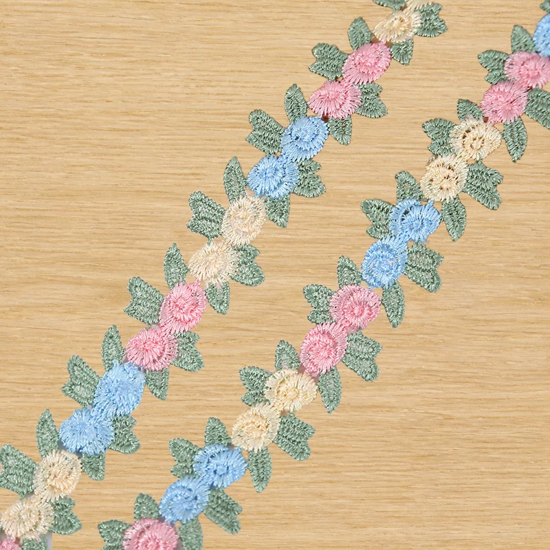 Soft pastel linked blooms lace trim — Photographed decorative trim sample; verify colour and construction with a physical sample